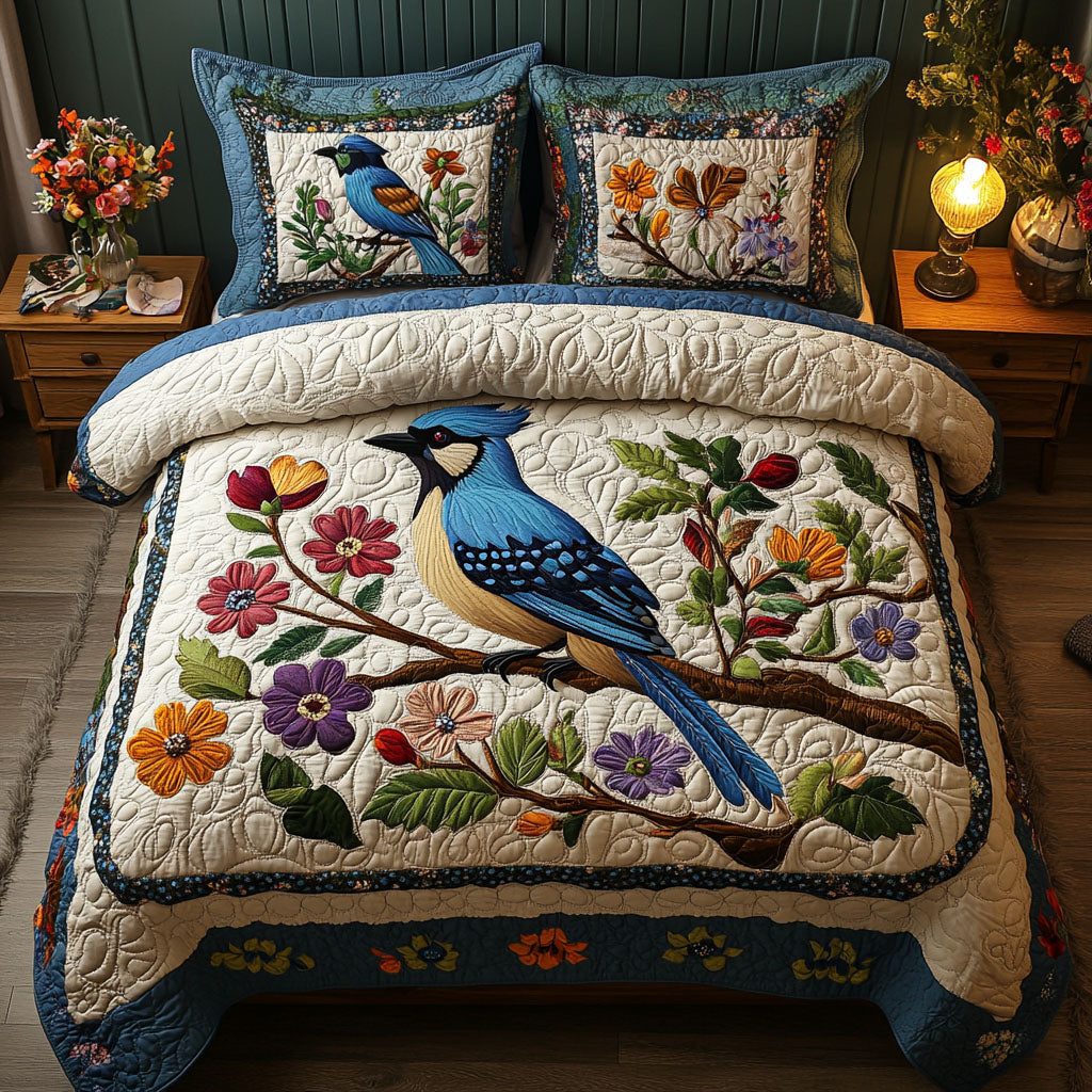 Blue Jay and Blooms quilted 3-piece bedding set on a made bed with two matching pillow shams