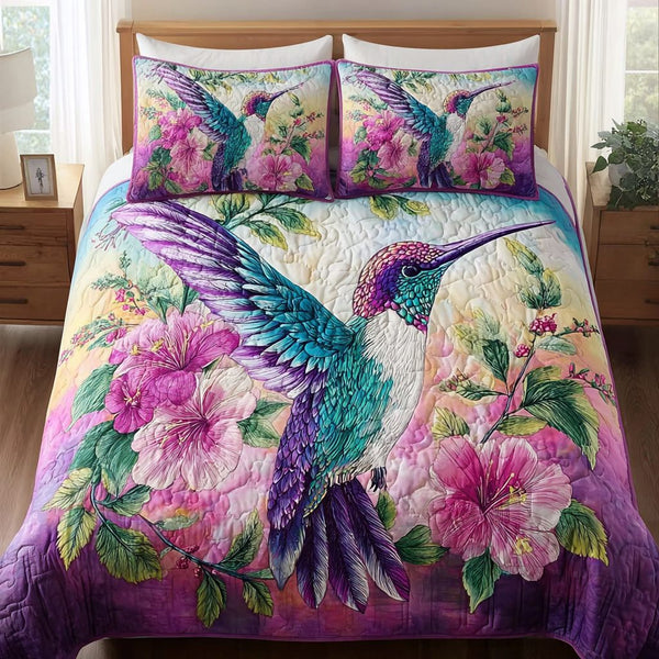 Hummingbird Dawn quilted 3-piece bedding set on a made bed with two matching pillow shams