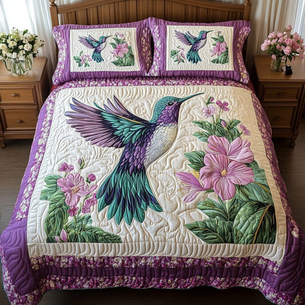 Hummingbird Glow quilted 3-piece bedding set on a made bed with two matching pillow shams