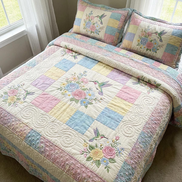 Hummingbird Haven quilted 3-piece bedding set on a made bed with two matching pillow shams