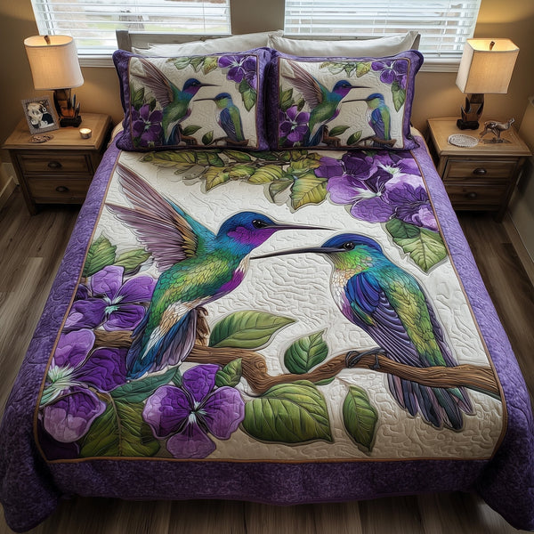 Amethyst Hummingbird Love quilted 3-piece bedding set on a made bed with two matching pillow shams