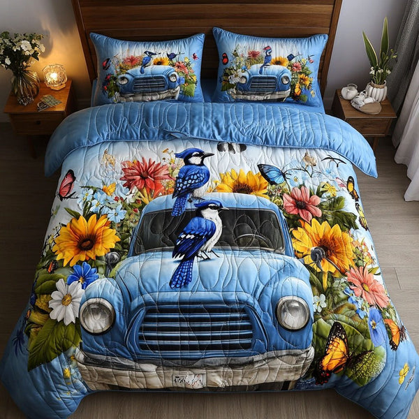Blossom Blue Jays quilted 3-piece bedding set on a made bed with two matching pillow shams