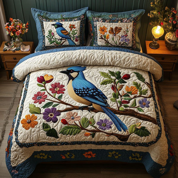 Blue Jay and Blooms quilted 3-piece bedding set on a made bed with two matching pillow shams