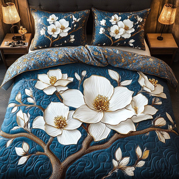 Blue Magnolia Elegance quilted 3-piece bedding set on a made bed with two matching pillow shams