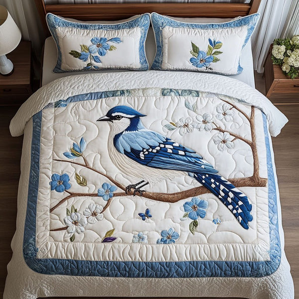 Bluebird Blossoms quilted 3-piece bedding set on a made bed with two matching pillow shams