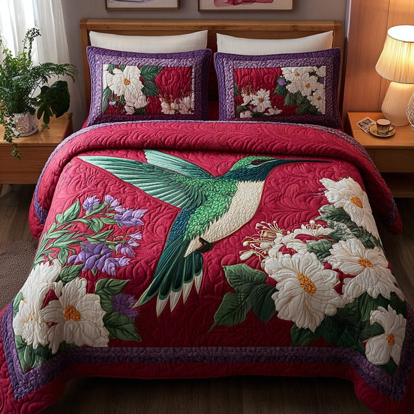 Hummingbird Bloom quilted 3-piece bedding set on a made bed with two matching pillow shams