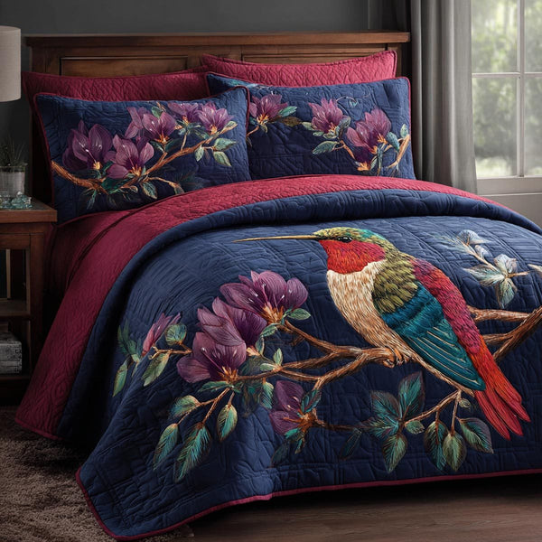 Hummingbird Bloom quilted 3-piece bedding set on a made bed with two matching pillow shams