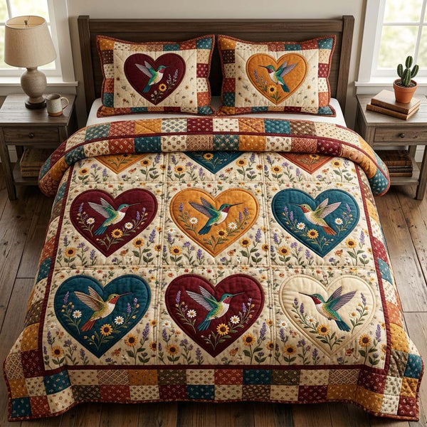 Hummingbird Grace quilted 3-piece bedding set on a made bed with two matching pillow shams