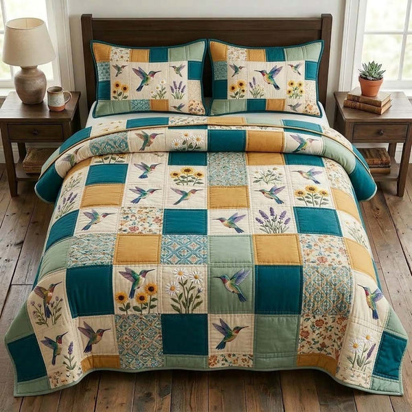 Hummingbird Grace quilted 3-piece bedding set on a made bed with two matching pillow shams