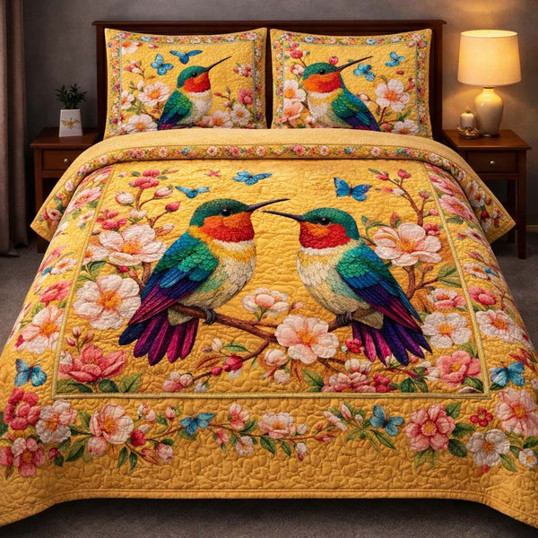 Hummingbird Heaven quilted 3-piece bedding set on a made bed in a softly lit bedroom