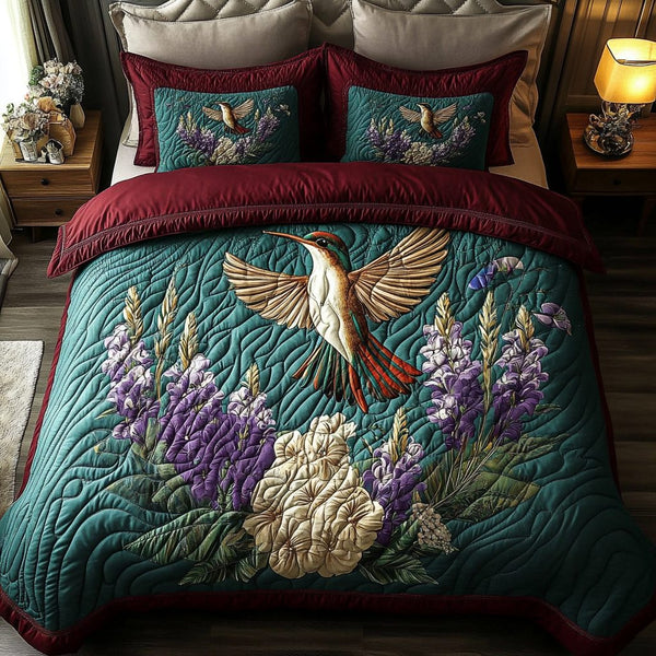 Hummingbird Whispers quilted 3-piece bedding set on a made bed with two matching pillow shams