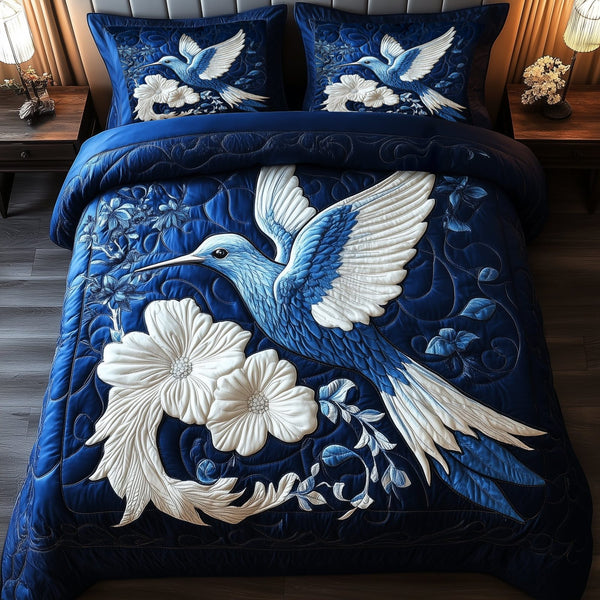Indigo Whisper Hummingbird quilted 3-piece bedding set on a made bed with two matching pillow shams