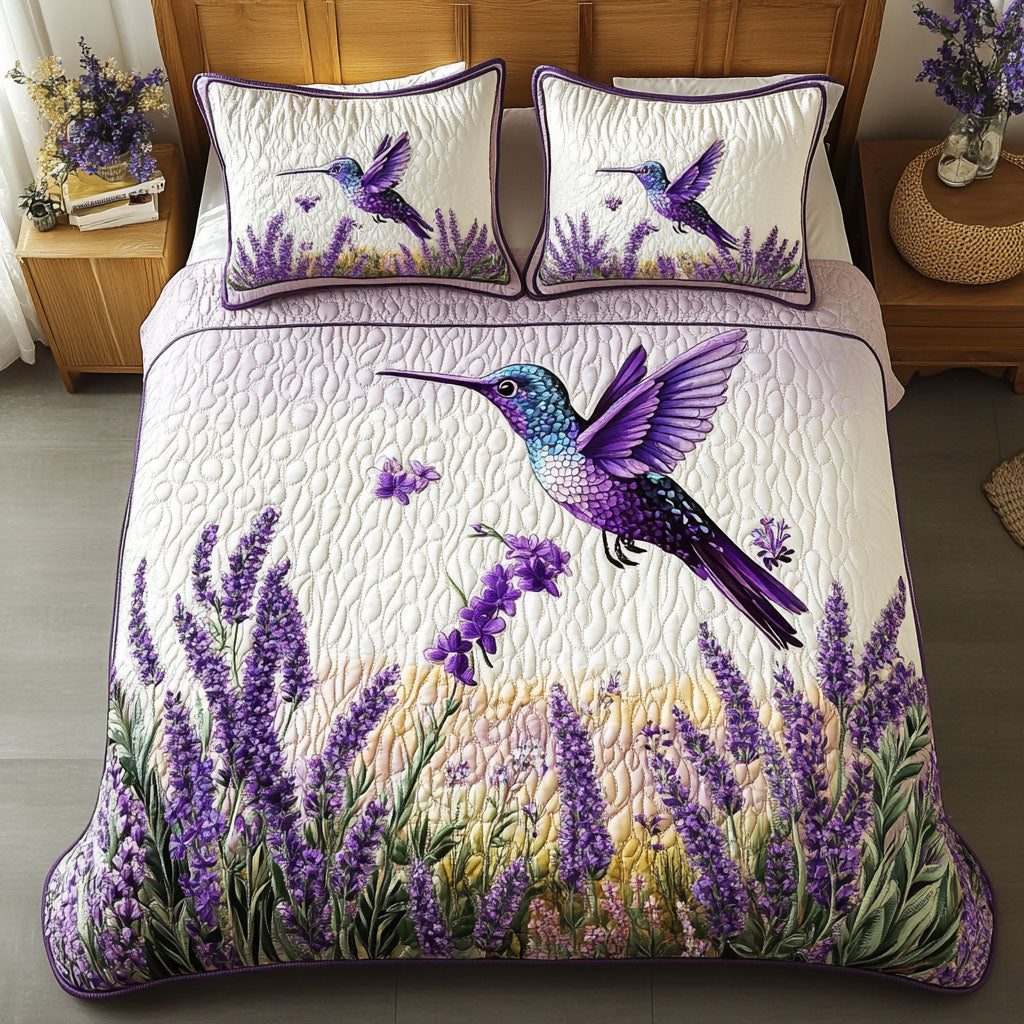 Lavender Hummingbird quilted 3-piece bedding set on a made bed with two matching pillow shams