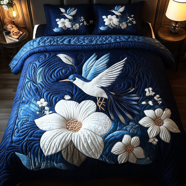 Midnight Bloom Hummingbird quilted 3-piece bedding set on a made bed with two matching pillow shams