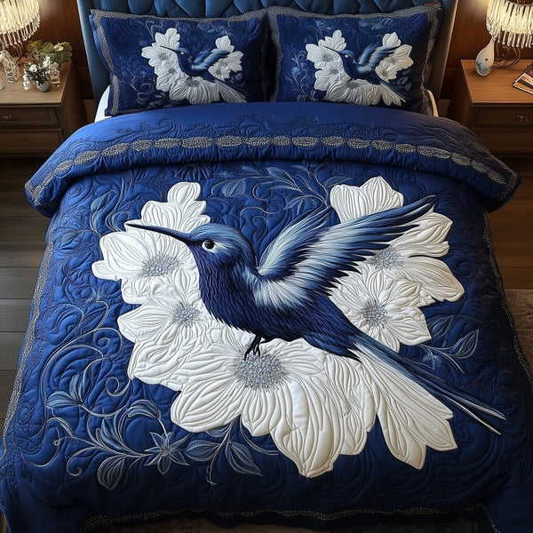 Royal Blue Hummingbird quilted 3-piece bedding set on a made bed with two matching pillow shams