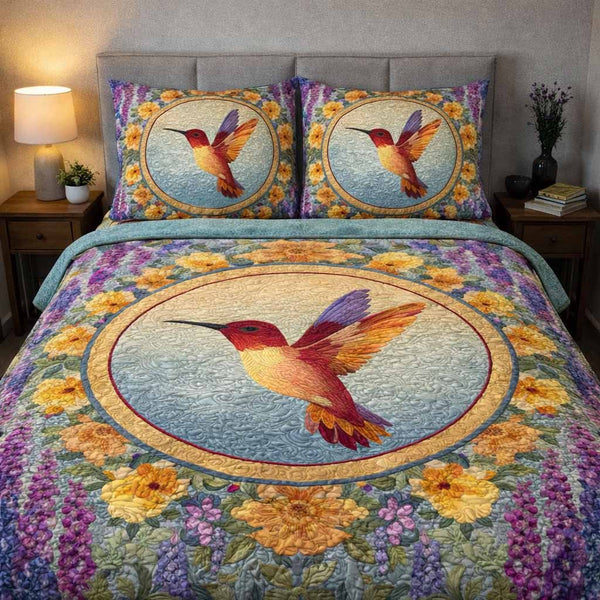 Sunrise Hummingbird quilted 3-piece bedding set on a made bed with two matching pillow shams