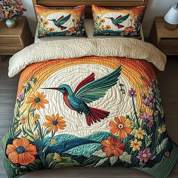 Sunset Hummingbird quilted 3-piece bedding set on a made bed with two matching pillow shams